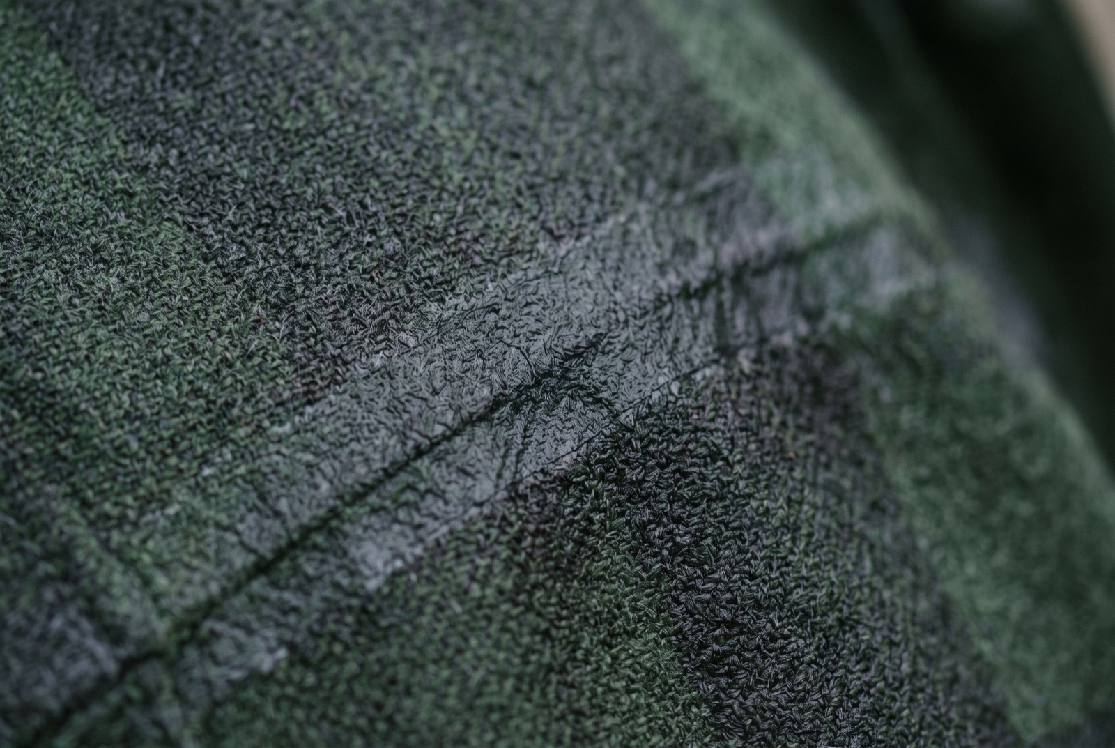 Close-up of a saturated jacket panel where the water has stopped beading and soaked into the face fabric