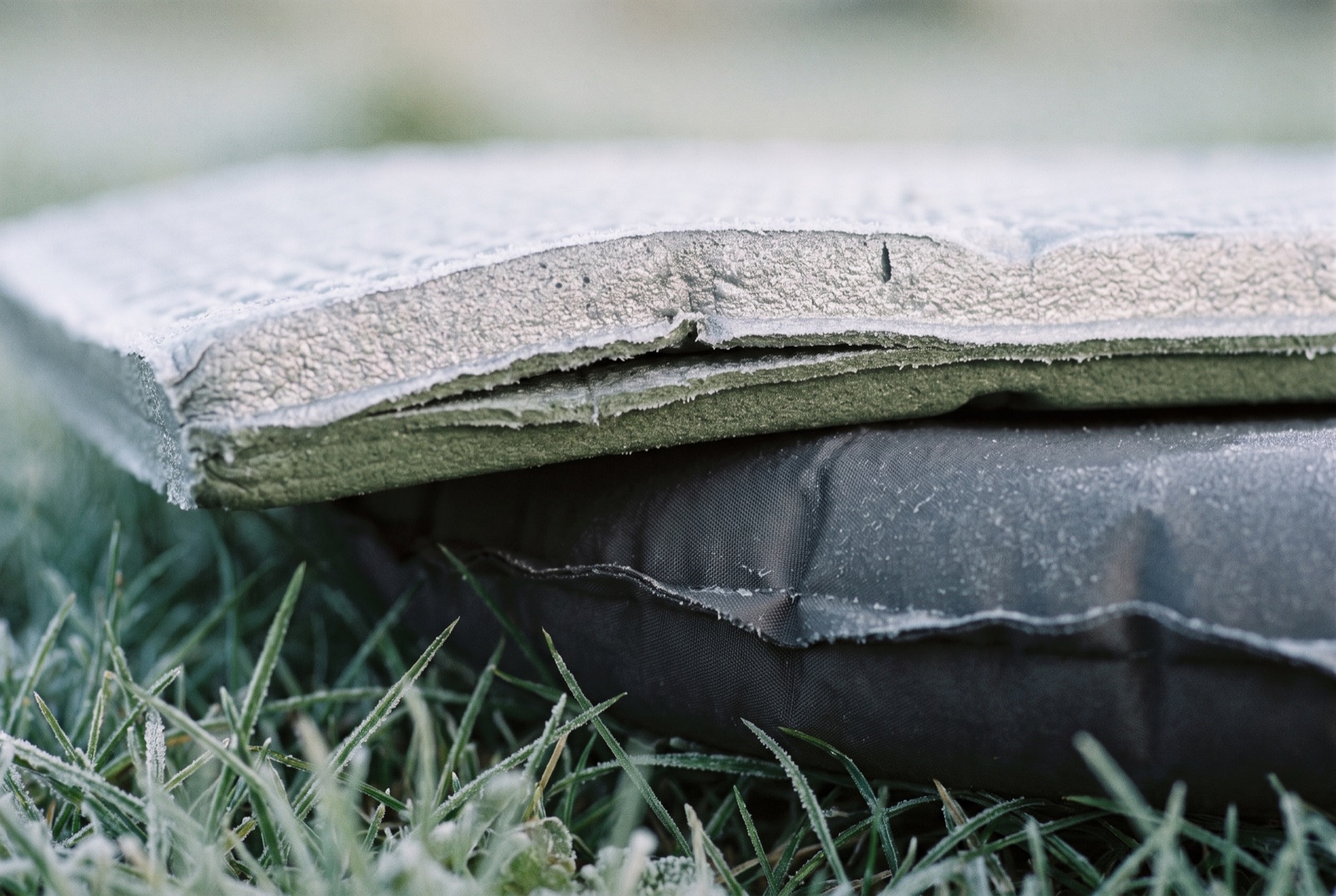 Close-up of a closed-cell foam mat layered on top of a self-inflating mat, with frosted grass beneath